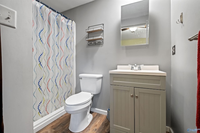 bathroom with a shower with shower curtain, hardwood / wood-style floors, vanity, and toilet