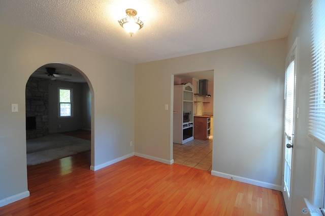 spare room featuring ceiling fan, a fireplace, wood-type flooring, and a textured ceiling