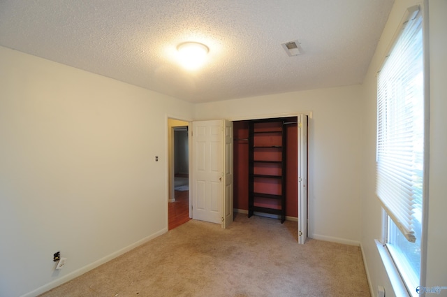 unfurnished bedroom featuring multiple windows, a closet, and light colored carpet