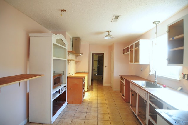 kitchen featuring sink, a textured ceiling, stainless steel microwave, and light tile patterned floors