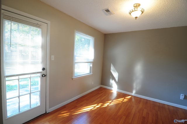 doorway with a textured ceiling and hardwood / wood-style flooring