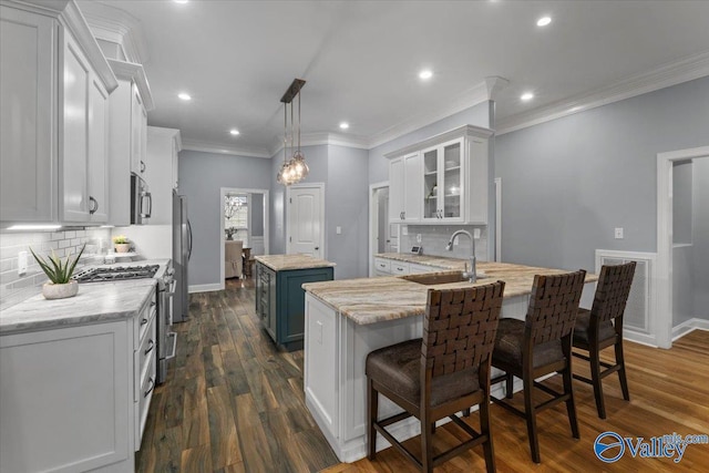 kitchen with white cabinetry, stainless steel appliances, a center island, sink, and a kitchen breakfast bar