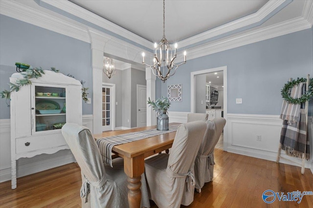 dining room featuring a raised ceiling, crown molding, a chandelier, and wood-type flooring