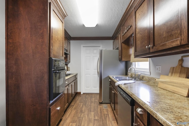 kitchen with crown molding, a sink, appliances with stainless steel finishes, dark wood-style floors, and dark brown cabinetry