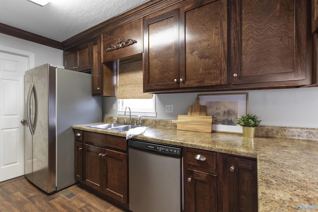 kitchen featuring a sink, stainless steel appliances, dark brown cabinetry, ornamental molding, and dark wood finished floors