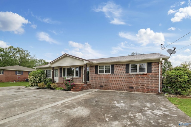 ranch-style house featuring covered porch, metal roof, crawl space, and brick siding