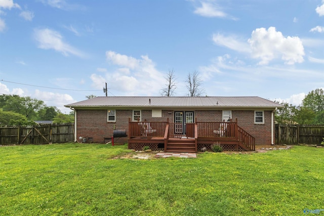 back of house featuring brick siding, a fenced backyard, a wooden deck, and a lawn