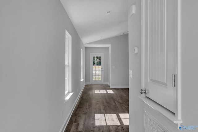 hall with dark wood-style floors, lofted ceiling, and baseboards