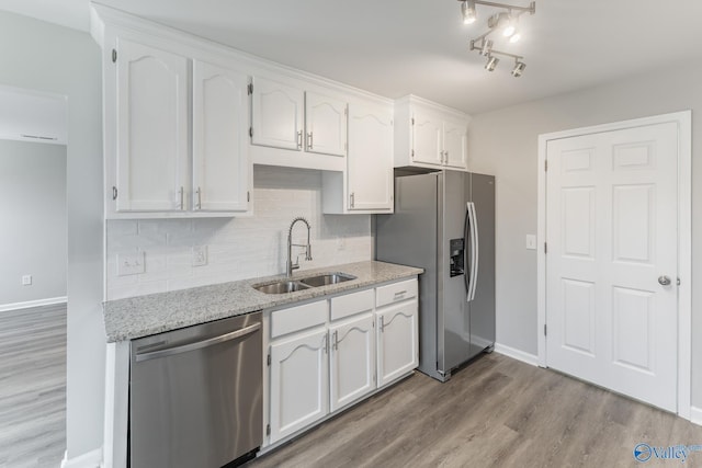 kitchen featuring light wood-type flooring, light stone counters, stainless steel appliances, sink, and white cabinets