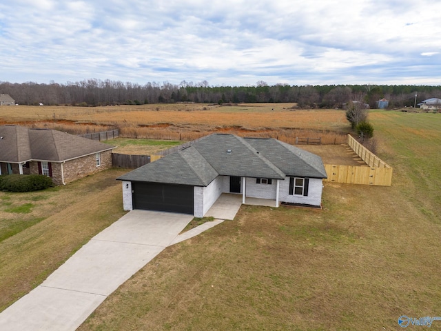 ranch-style home featuring a rural view, a garage, and a front yard