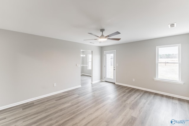 spare room with ceiling fan, a healthy amount of sunlight, and light hardwood / wood-style floors