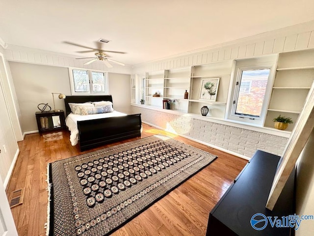 bedroom featuring crown molding, ceiling fan, wood-type flooring, and multiple windows