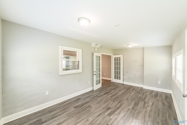 spare room featuring wood finished floors, french doors, and baseboards