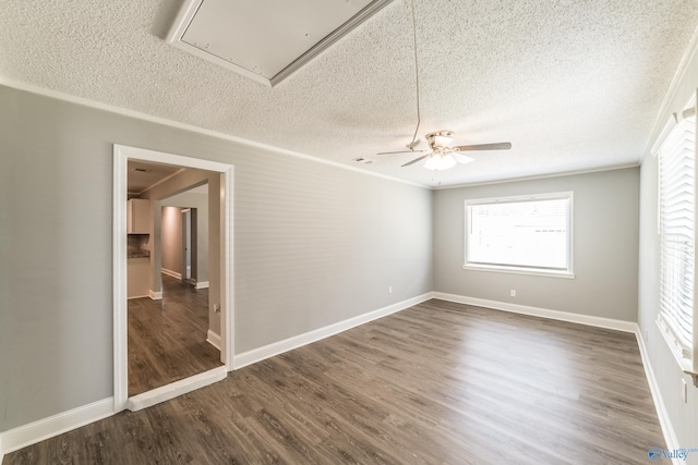 empty room with a textured ceiling, attic access, ceiling fan, dark wood-style flooring, and baseboards
