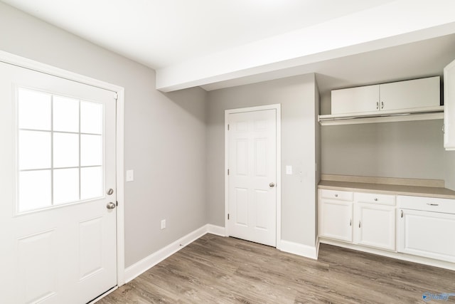 doorway featuring baseboards and light wood-type flooring