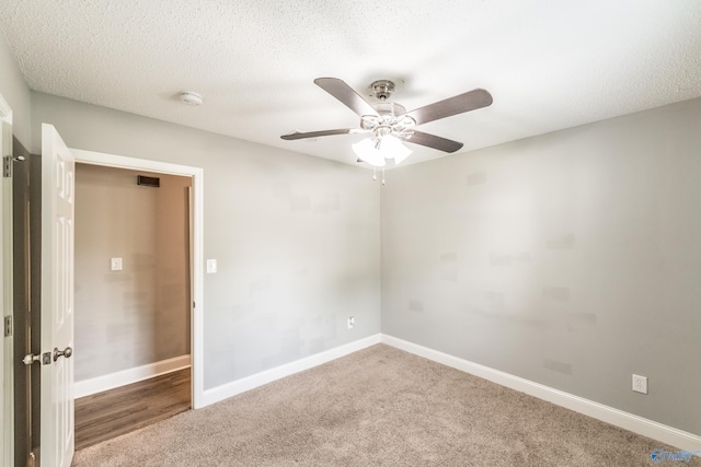 carpeted spare room with a textured ceiling, baseboards, and a ceiling fan