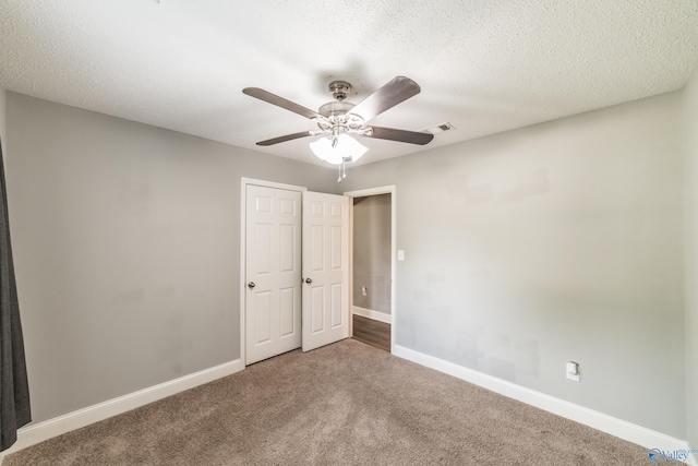 unfurnished bedroom featuring a textured ceiling, carpet flooring, baseboards, and visible vents