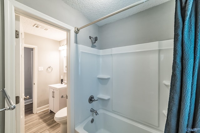 bathroom featuring wood finished floors, vanity, a textured ceiling, visible vents, and shower / tub combo