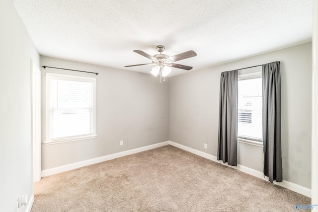 empty room with a ceiling fan, carpet, plenty of natural light, and baseboards