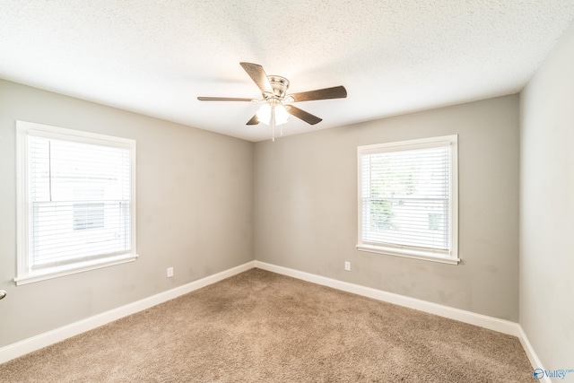carpeted spare room with a textured ceiling, baseboards, and a ceiling fan