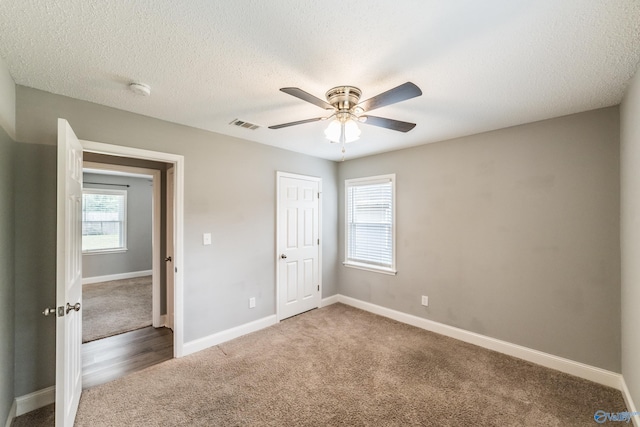 unfurnished bedroom featuring baseboards, carpet flooring, visible vents, and a textured ceiling