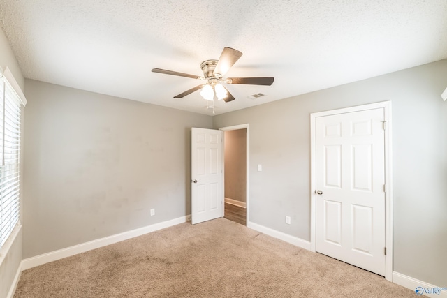 unfurnished bedroom with baseboards, a ceiling fan, visible vents, and carpet