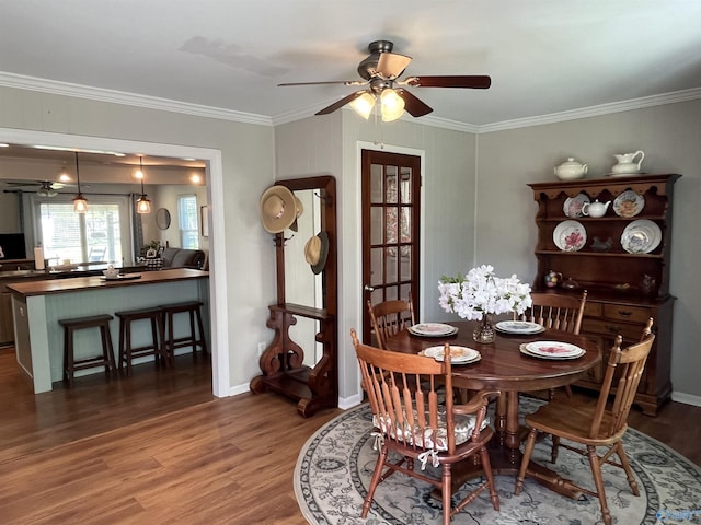 dining space featuring ornamental molding, baseboards, a ceiling fan, and wood finished floors