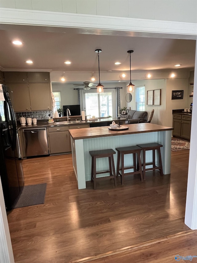 kitchen with stainless steel dishwasher, dark wood finished floors, butcher block counters, recessed lighting, and a breakfast bar area