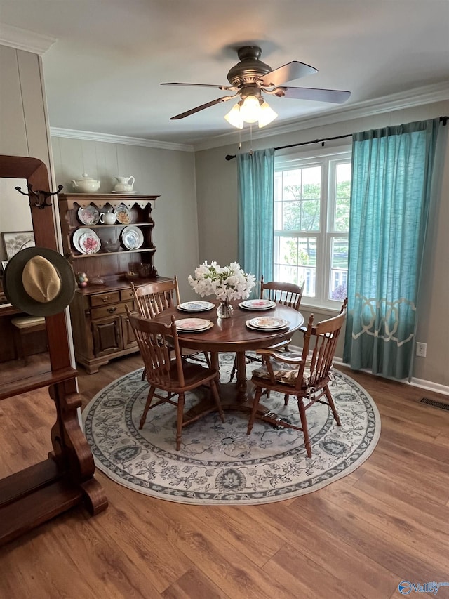 dining area with crown molding, wood finished floors, ceiling fan, and visible vents