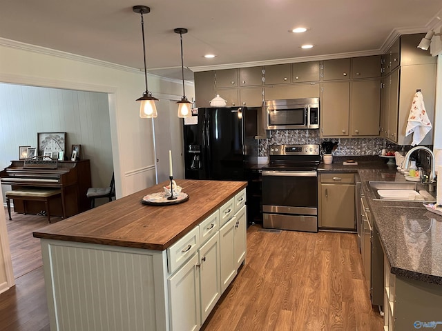 kitchen featuring a sink, ornamental molding, wood finished floors, stainless steel appliances, and butcher block countertops