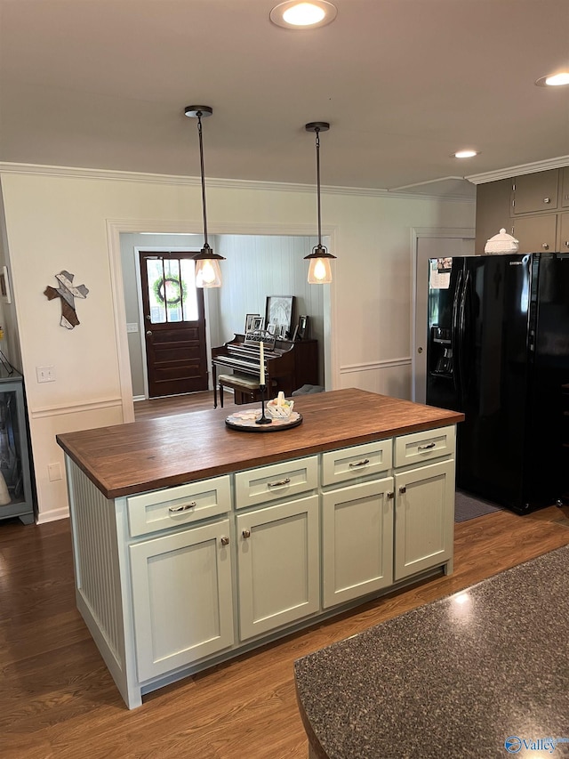 kitchen featuring butcher block countertops, crown molding, and black fridge with ice dispenser