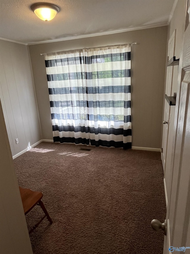 spare room with crown molding, dark colored carpet, baseboards, and a textured ceiling