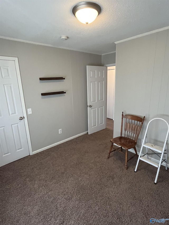 sitting room featuring a textured ceiling, baseboards, ornamental molding, and carpet