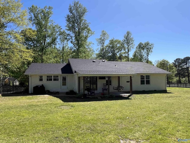rear view of house with fence, a patio, a lawn, and roof with shingles