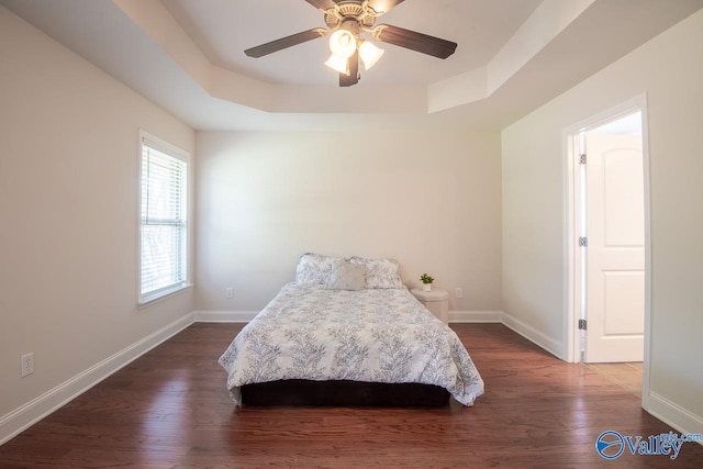 bedroom featuring a tray ceiling, ceiling fan, and dark wood-type flooring