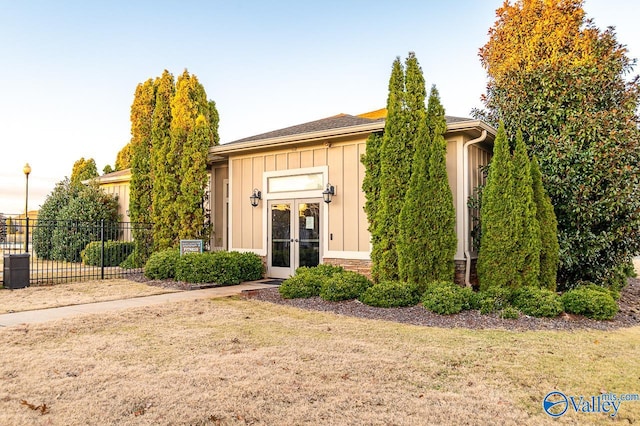 view of front of home with french doors and a front lawn