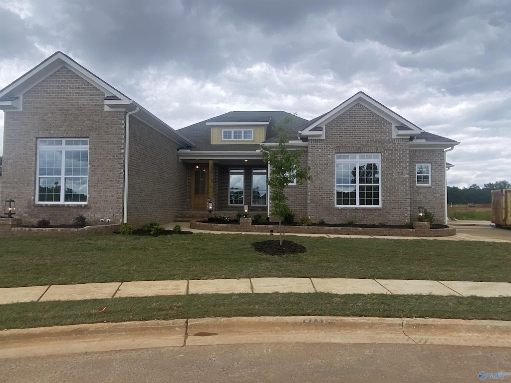 view of front facade with brick siding and a front lawn