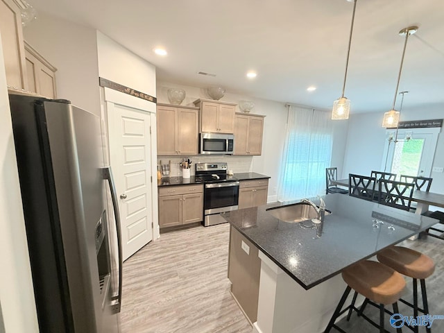 101 River Springs Ct, New Market, AL 35761 - kitchen featuring appliances with stainless steel finishes, a sink, light wood-style floors, a breakfast bar, and an island with sink