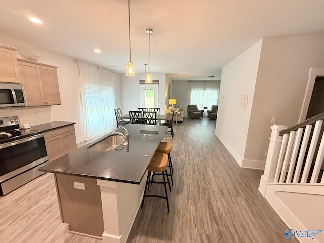 101 River Springs Ct, New Market, AL 35761 - kitchen with appliances with stainless steel finishes, a sink, dark countertops, light wood-style flooring, and a kitchen breakfast bar