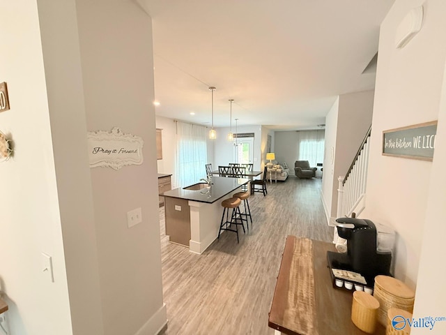 101 River Springs Ct, New Market, AL 35761 - kitchen with a breakfast bar area, light wood-type flooring, dark countertops, a kitchen island with sink, and open floor plan