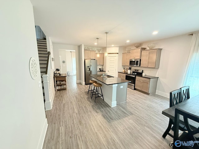 101 River Springs Ct, New Market, AL 35761 - kitchen with appliances with stainless steel finishes, dark countertops, baseboards, light wood-type flooring, and a kitchen bar