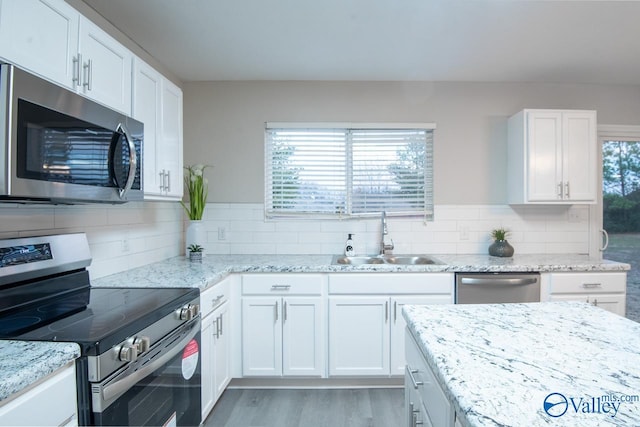 kitchen featuring appliances with stainless steel finishes, sink, a wealth of natural light, and white cabinets