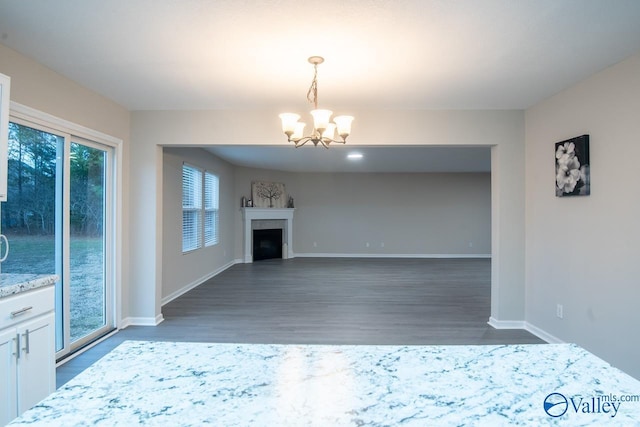 unfurnished living room featuring a notable chandelier and dark hardwood / wood-style floors