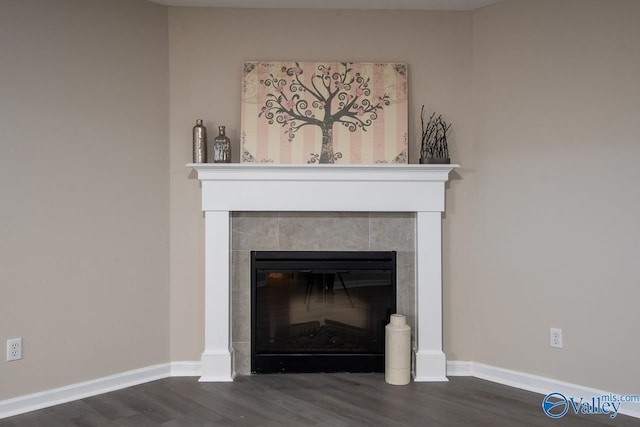 interior details featuring a tiled fireplace and wood-type flooring