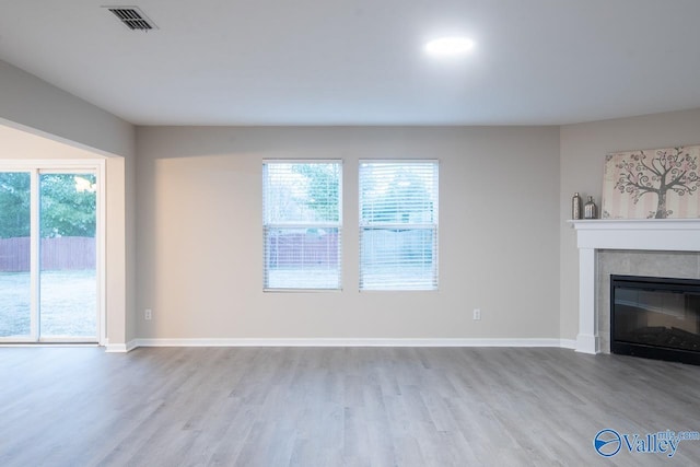 unfurnished living room featuring light wood-type flooring, a wealth of natural light, and a fireplace