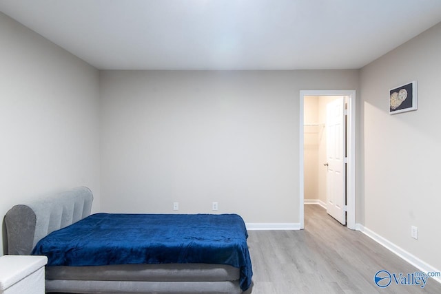 bedroom featuring a walk in closet and light hardwood / wood-style flooring