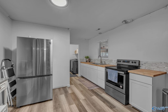 kitchen with appliances with stainless steel finishes, butcher block countertops, white cabinetry, and sink