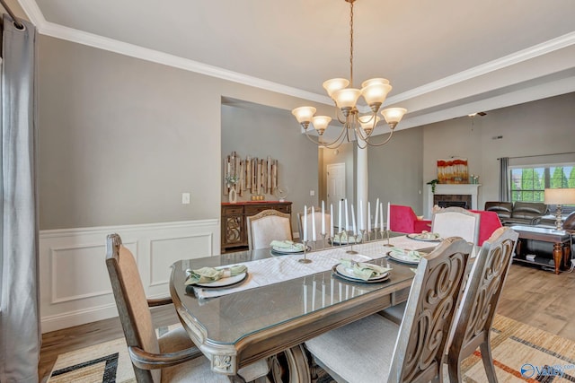 dining room with ornamental molding, light wood-style floors, and an inviting chandelier