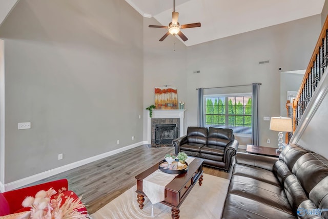 living room featuring a tile fireplace, stairway, wood finished floors, and a high ceiling