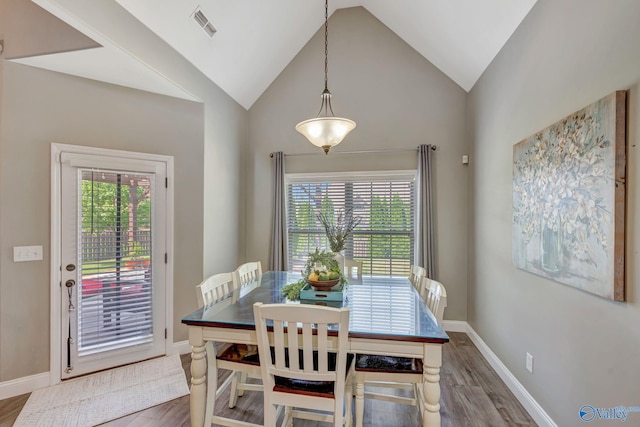 dining area with vaulted ceiling, visible vents, and wood finished floors